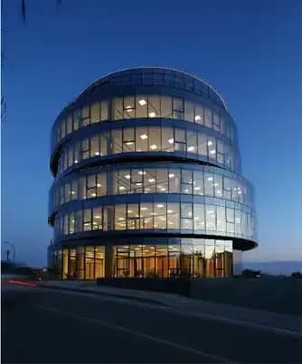 Modern circular office building with illuminated glass facade at night